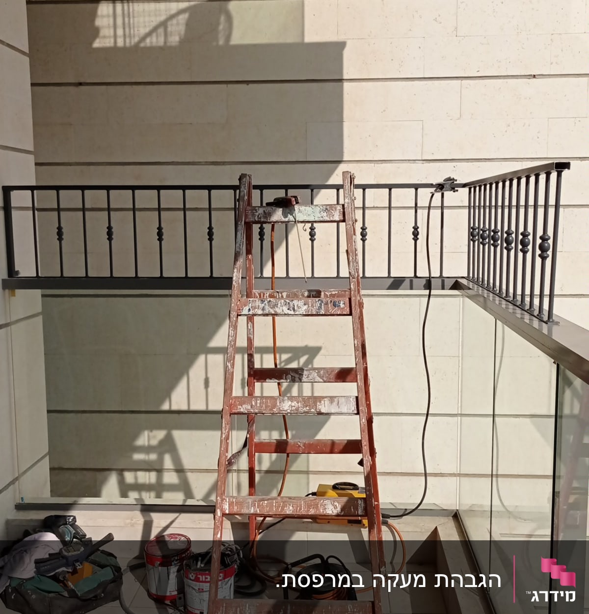 סולם עץ מול מעקה מתכת עם כלים על הרצפה